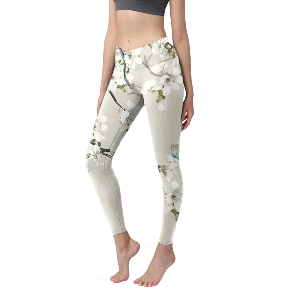Cream-colored high waisted yoga leggings with a delicate floral pattern of white blossoms green leaves and black branches