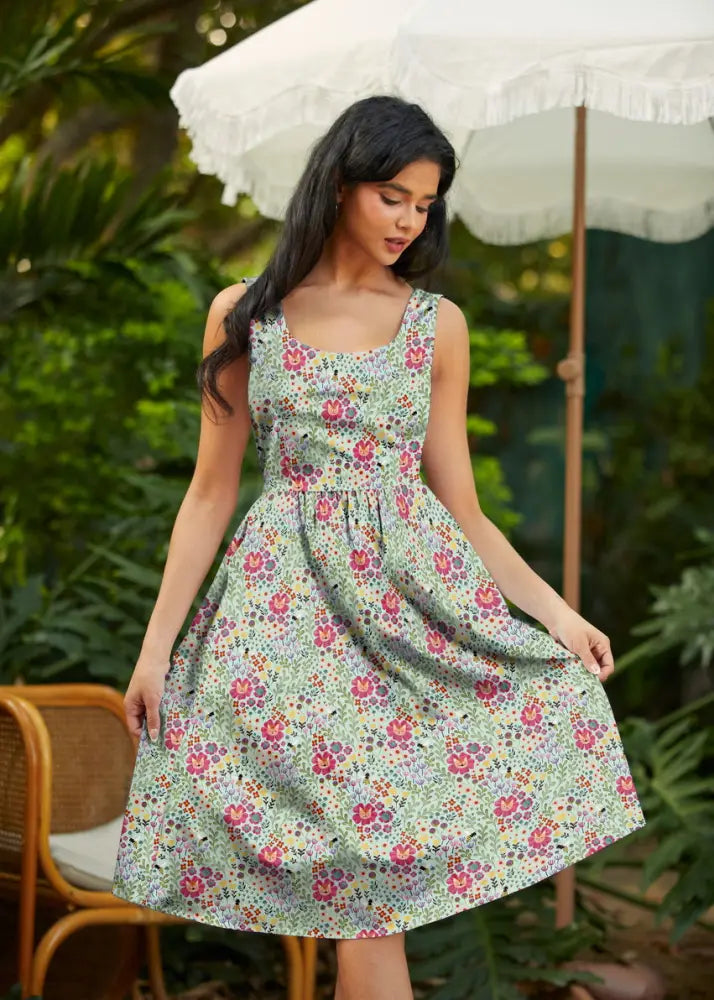 A sleeveless light green cotton a-line dress with vibrant pink and purple floral pattern and pockets