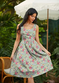 A sleeveless light green cotton a-line dress with vibrant pink and purple floral pattern and pockets