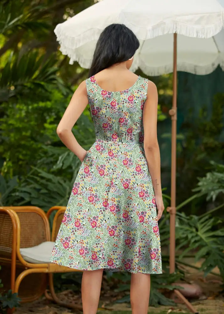 A sleeveless knee-length floral cats light green cotton a-line dress with pockets featuring pink red and purple blossoms