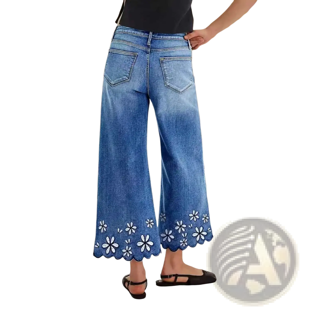 Blue denim wide-leg pants with scalloped hem and white floral embroidery in a cropped floral embroidered design
