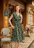 A woman wearing a floral Greta green vintage cotton v neck dress with pink yellow blossoms and short sleeves