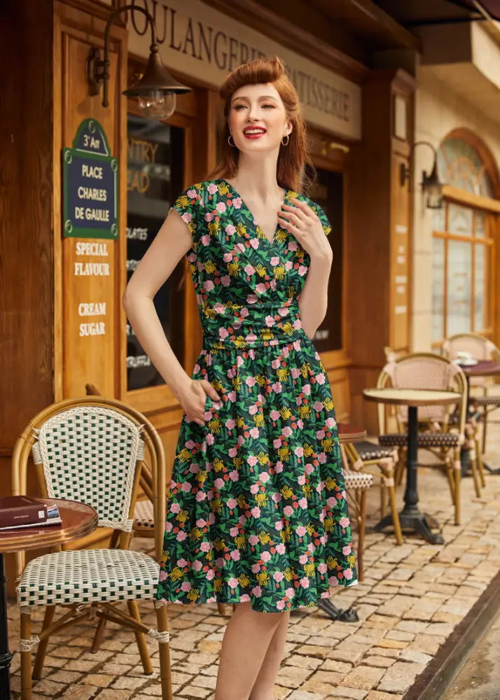A woman wearing a floral Greta green vintage cotton v neck dress with pink yellow blossoms and short sleeves