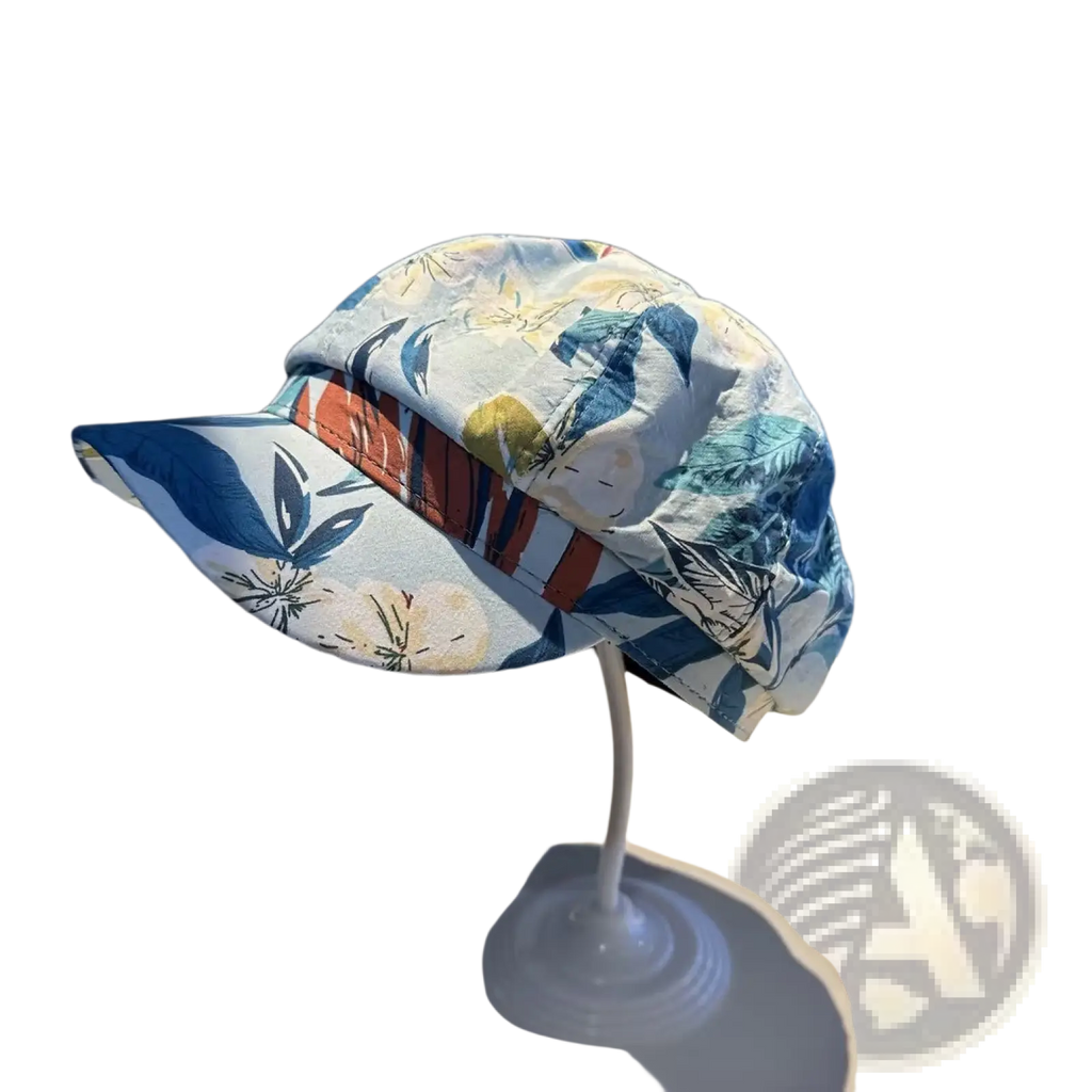A light blue floral newsboy cap with a striped orange and brown band displayed on a white stand