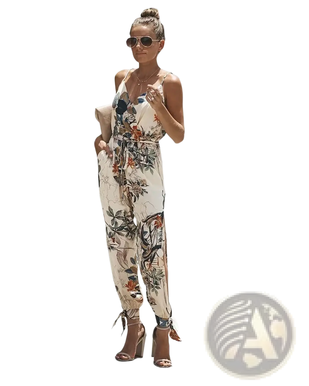 A woman wearing a beige floral print boho summer jumpsuit with thin straps and tied cuffs at the ankles