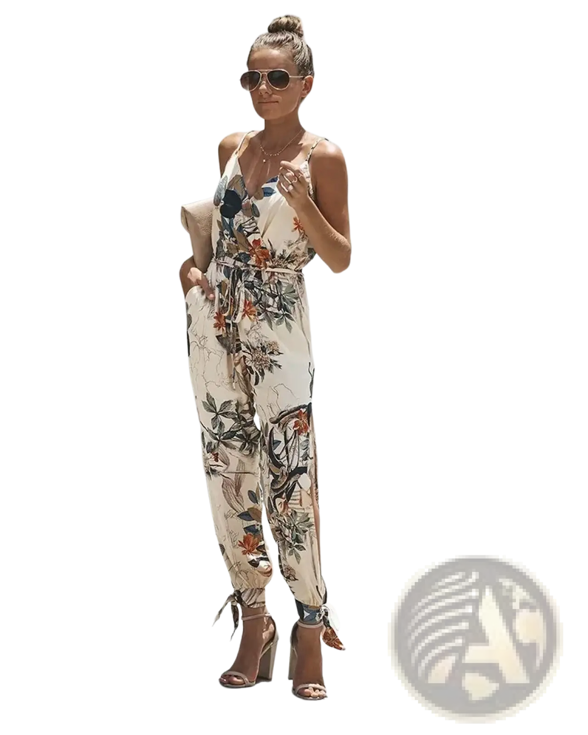 A woman wearing a beige floral print boho summer jumpsuit with thin straps and tied cuffs at the ankles