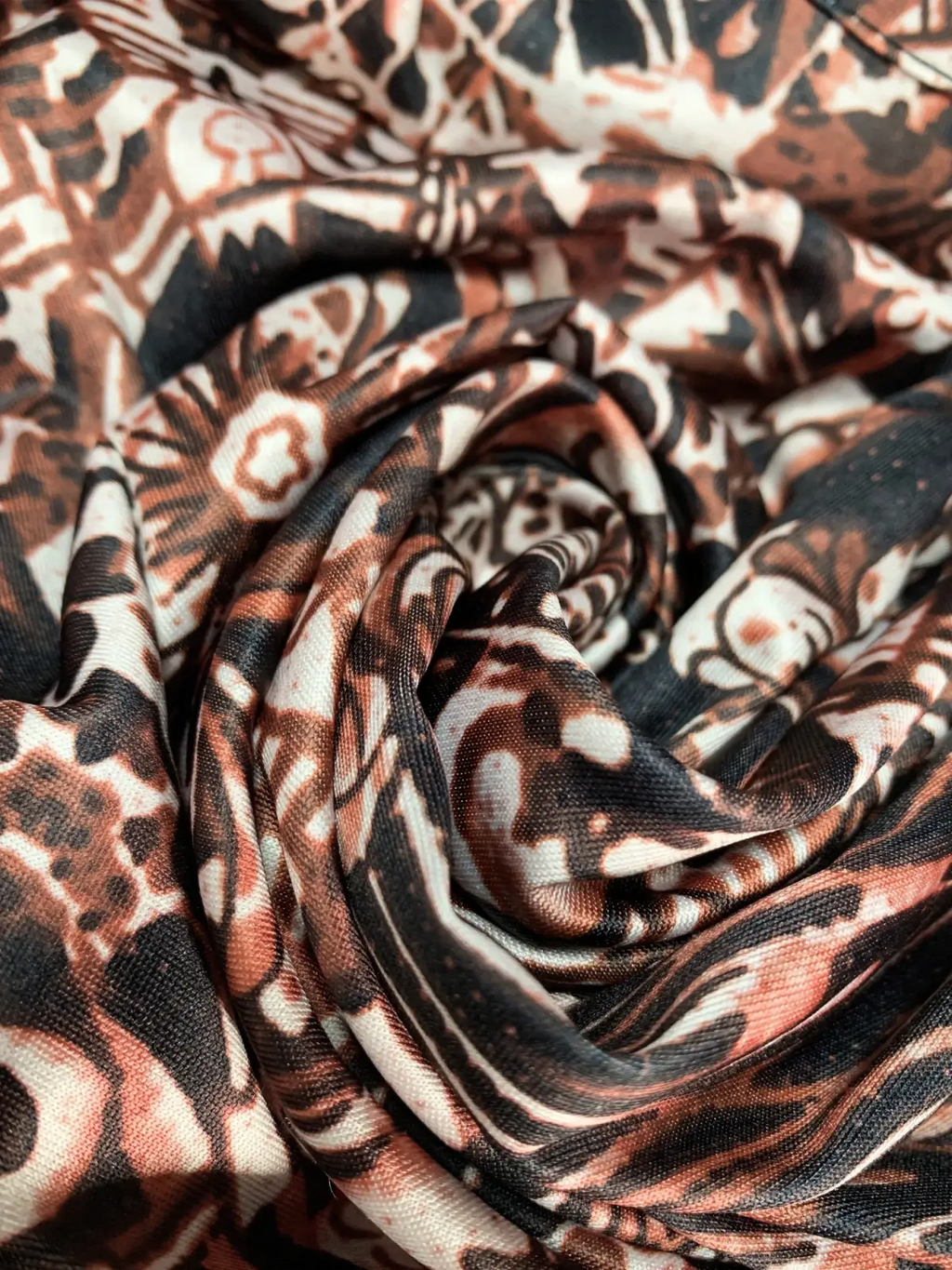 A soft flowing scarf with a bold abstract pattern in brown black and cream paired with a floral print maxi dress