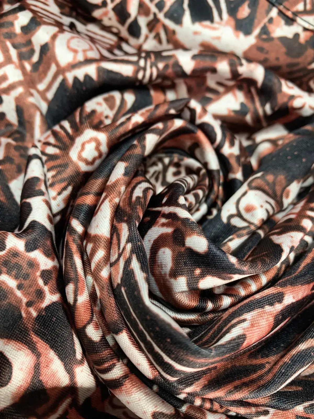 A soft flowing scarf with a bold abstract pattern in brown black and cream paired with a floral print maxi dress