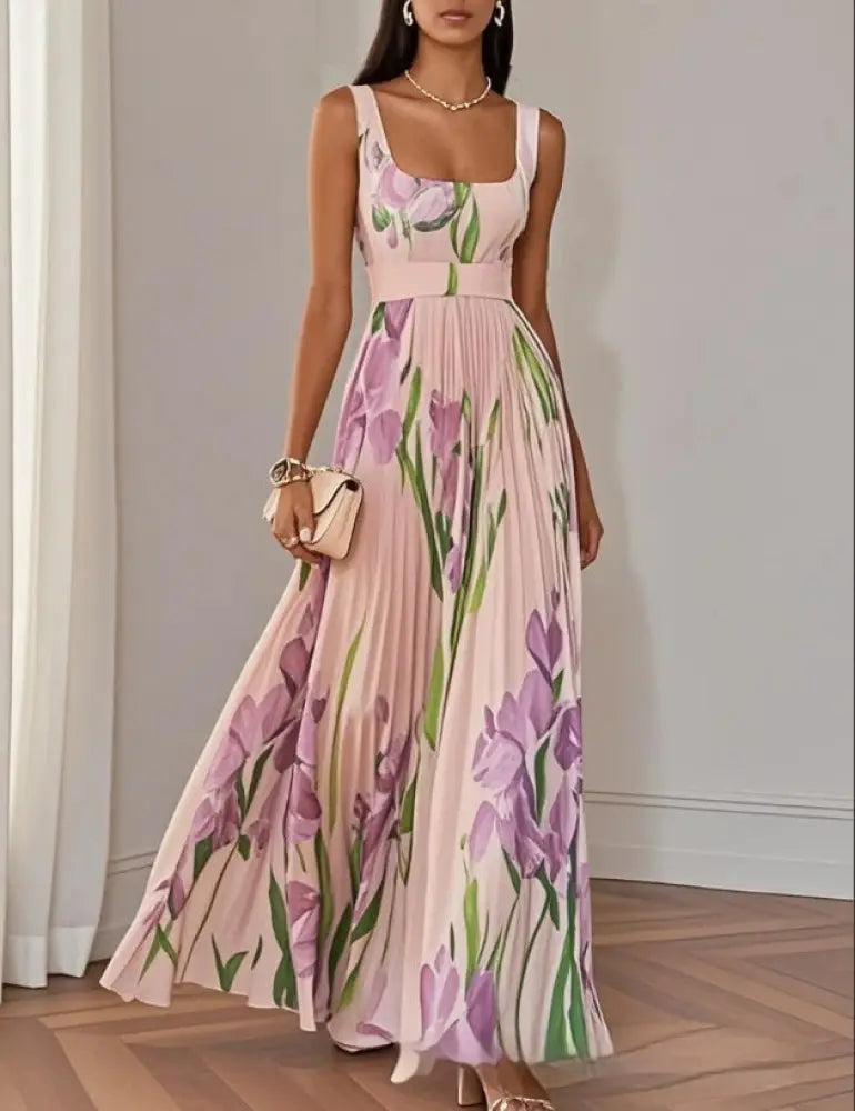 A flowing sleeveless soft pink maxi dress with vibrant purple iris print green stems square neckline fitted bodice and pleated skirt