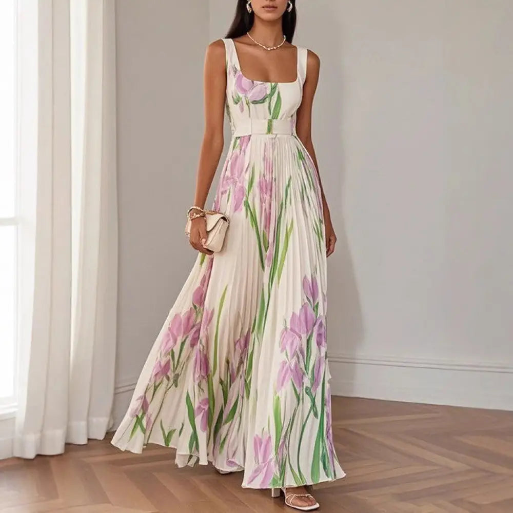 A flowing white floral iris pleated maxi dress with square neckline and thin straps featuring pink and green pattern