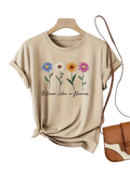Beige short sleeve casual t-shirt with colorful floral print and black cursive bloom like a flower phrase