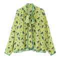 A light green floral two piece midi skirt set with black pattern teal trim long sleeves and tied neck detail