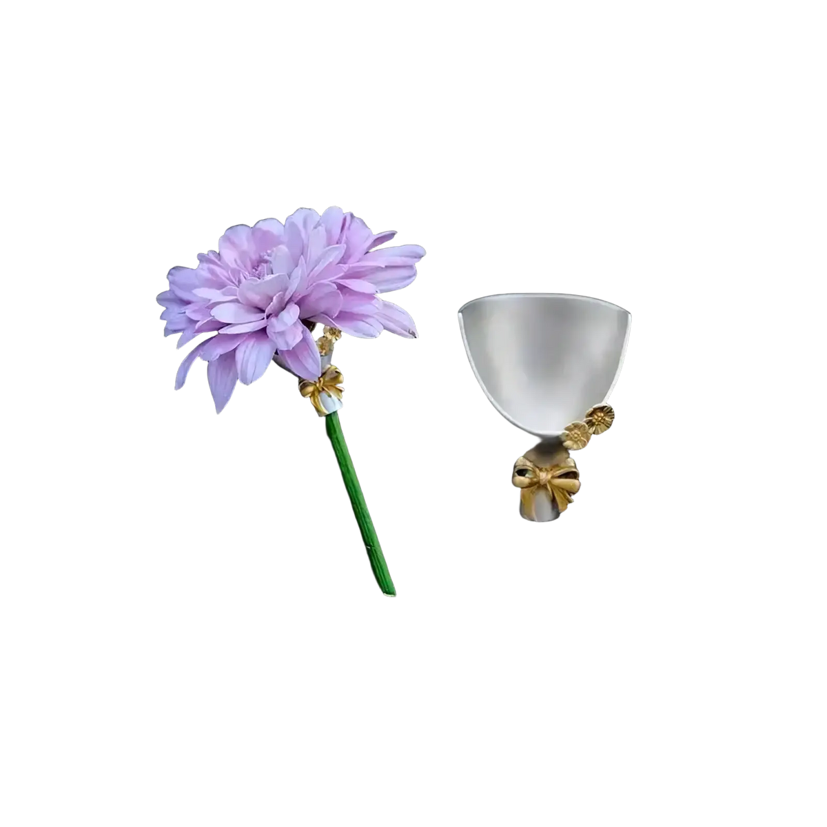 A delicate lavender flower brooch pin with green stem and gold bow beside a white ceramic cup with golden accents