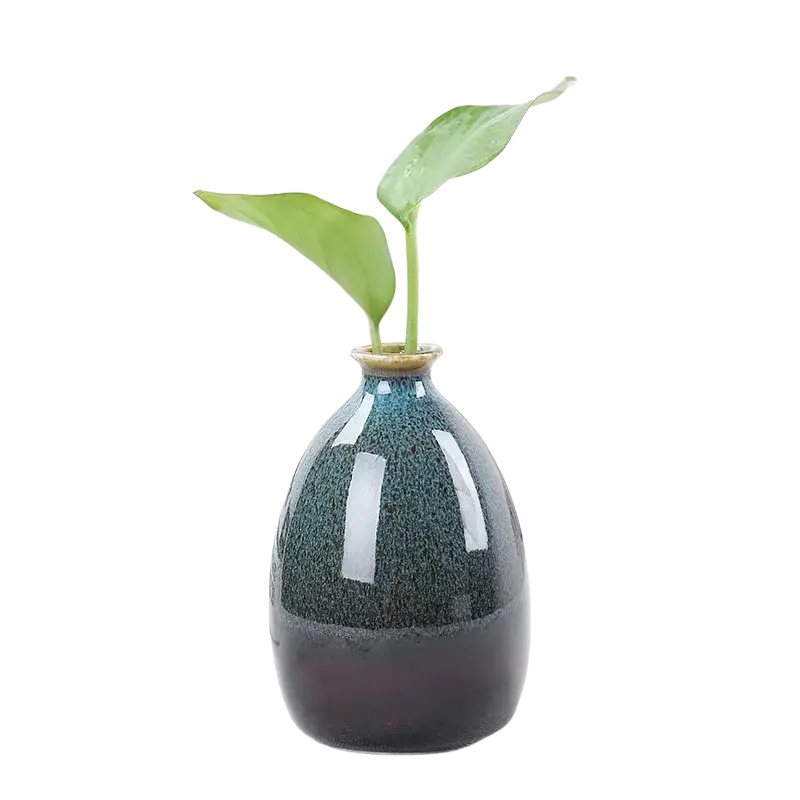 A sleek dark teal flower glaze ceramic vase with glossy speckled texture holding two vibrant green leaves
