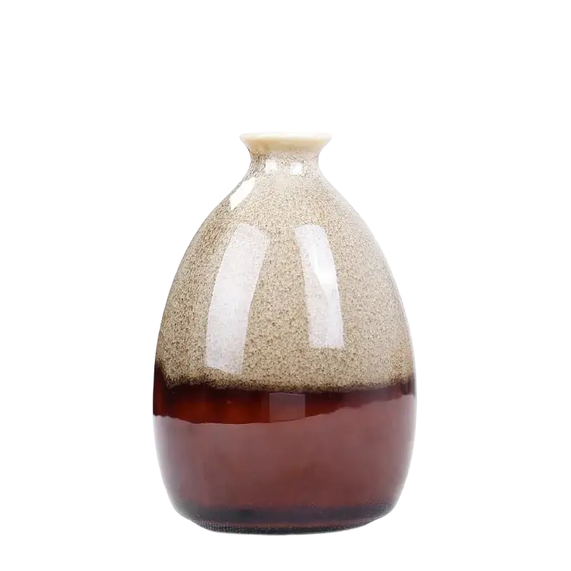 A small ceramic flower glaze vase with speckled beige and brown glaze and a rounded body tapering to a narrow neck
