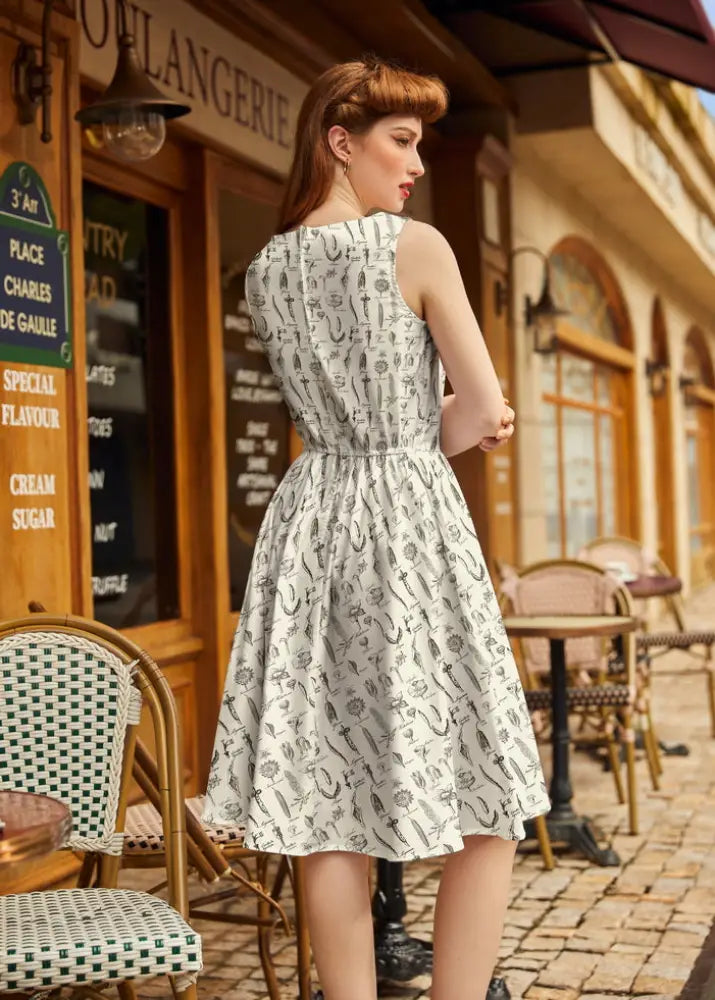 White cotton sleeveless a-line dress with black vintage tool print fitted bodice and flared skirt floral botanical theme