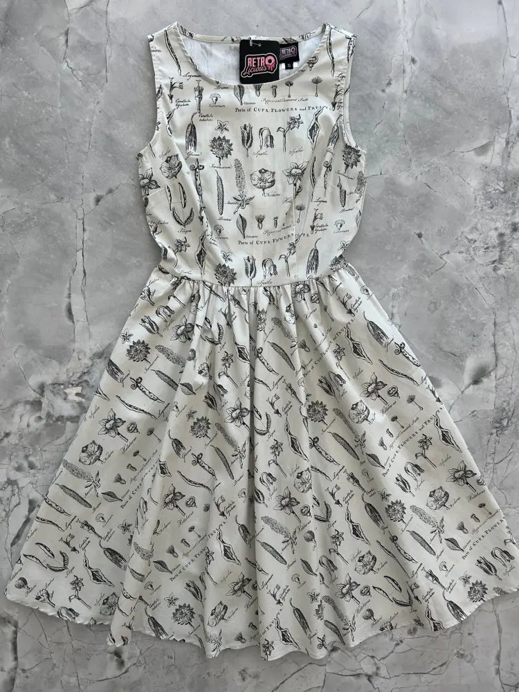 A sleeveless white cotton a-line dress with black botanical print and gathered waist from the flower parts collection
