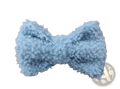 A soft light blue crocheted fluffy bow hair clip made of cream sheepskin with a textured surface