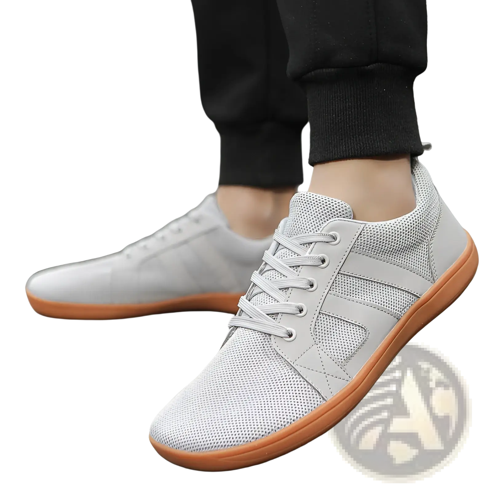 Light gray fly-knit wide last sneakers featuring breathable mesh, orange rubber soles, and matching laces