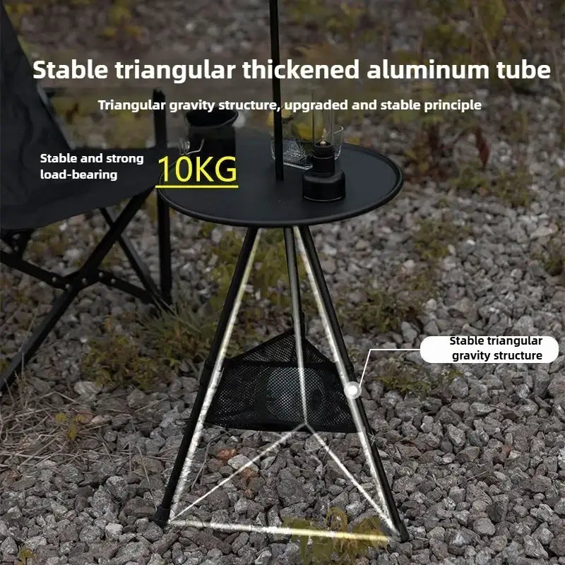 Black triangular foldable round table made of aluminum alloy with a mesh storage basket beneath the top for camping use
