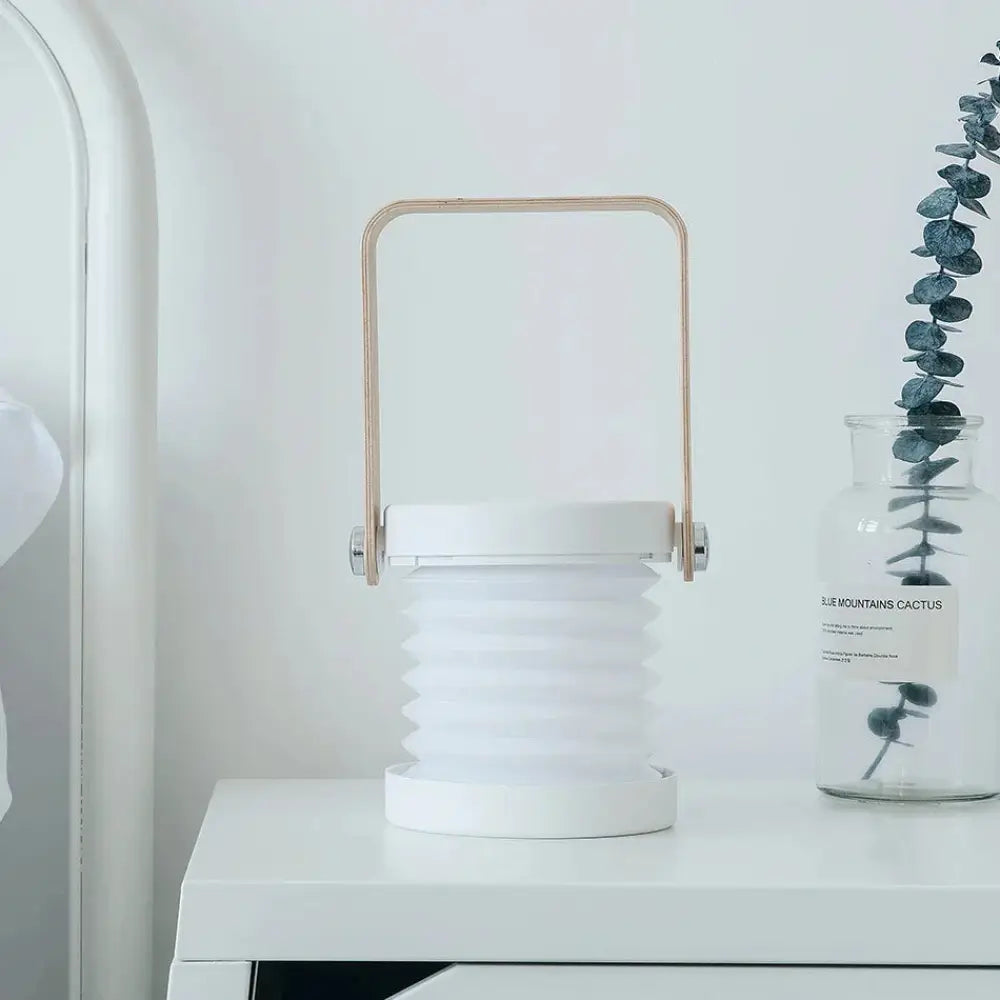 White foldable touch dimmable led lantern with a light wood handle for portable use as a table lamp