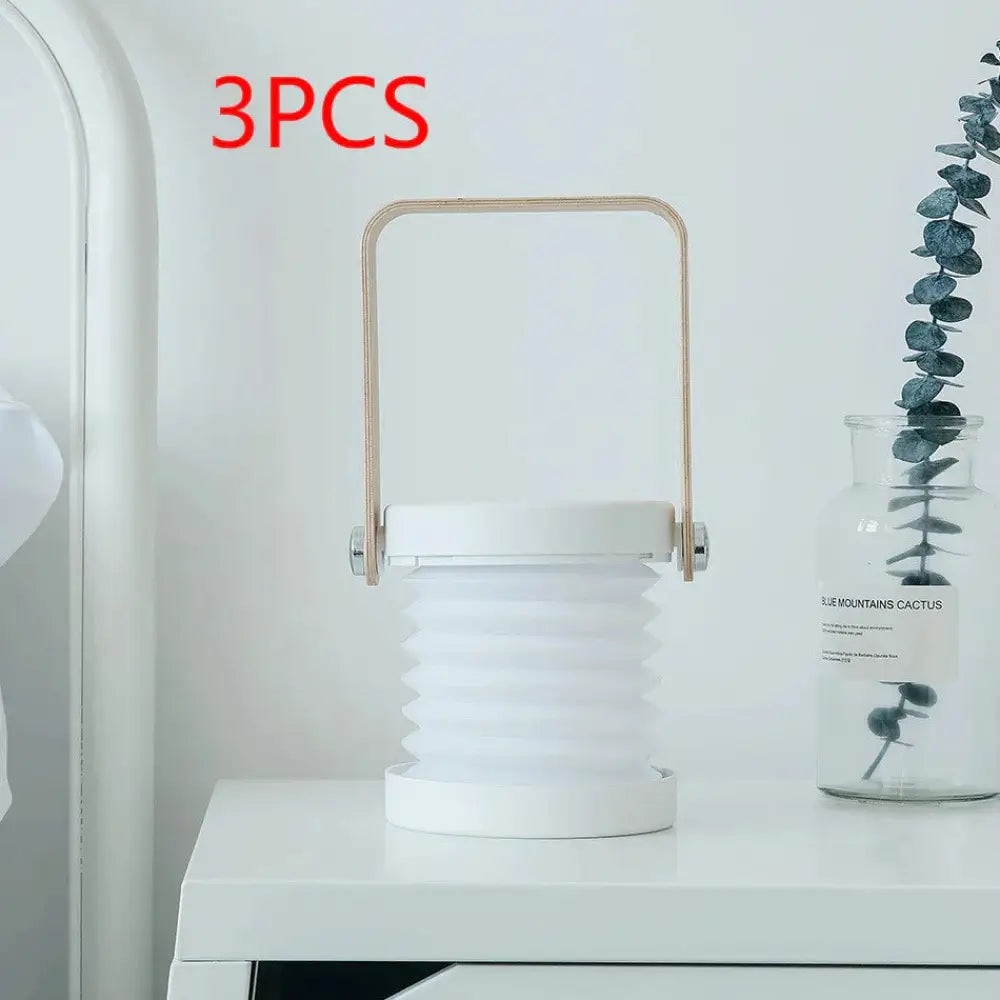 Foldable touch dimmable led lantern in white with gold-toned metal handle featuring collapsible design