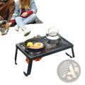 Black metal folding campfire grill with heavy duty steel mesh grate and legs positioned over open fire surrounded by rocks