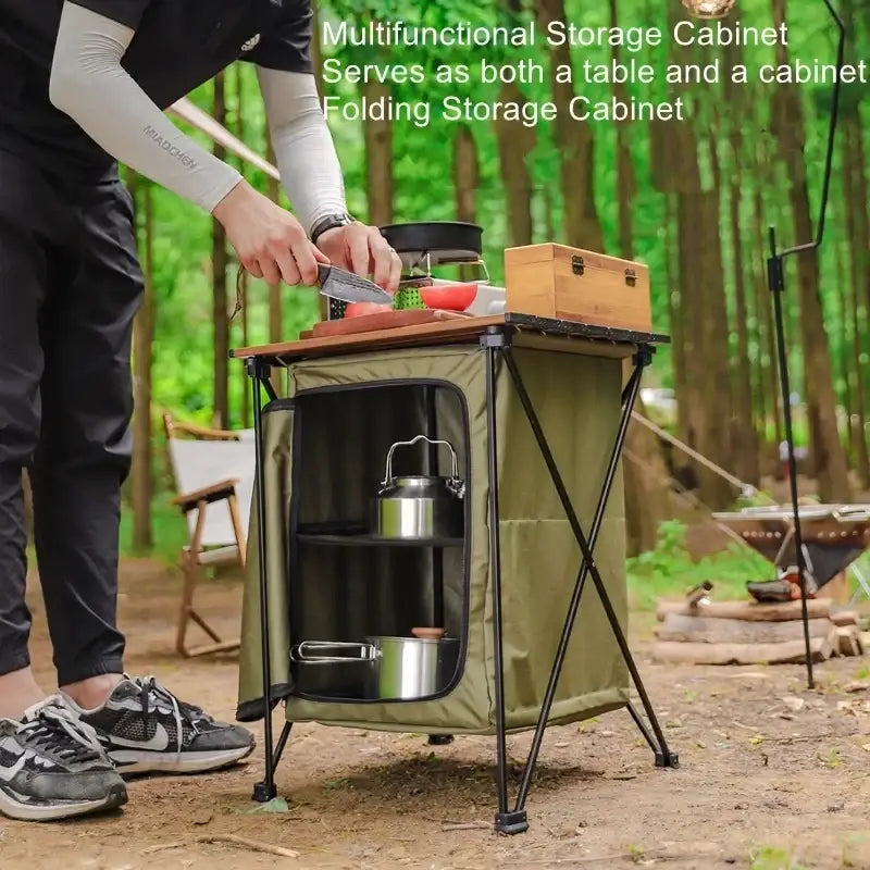 Olive green folding camping storage cabinet with black metal frame and wooden top designed for outdoor use