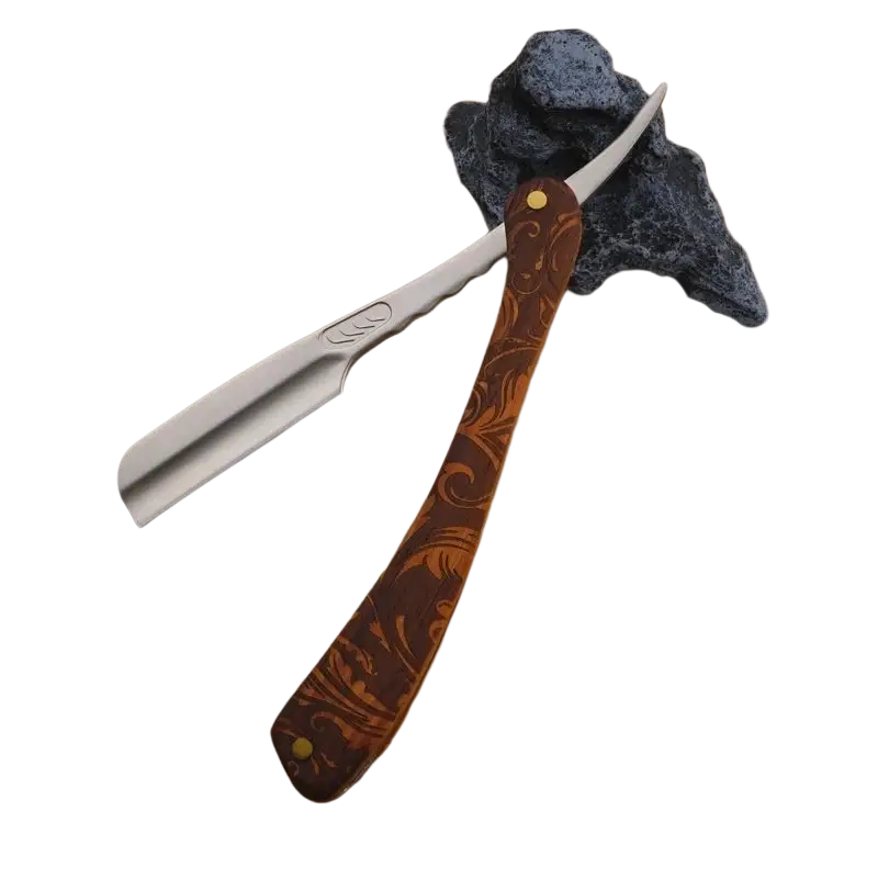 Folding razor with a polished silver blade and ornate brown wooden handle featuring intricate floral engraving and gold rivets