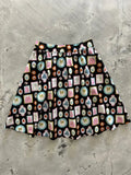 A black cotton vintage a-line skirt with pink and blue cartoon dog pattern framed in gold trim with pockets