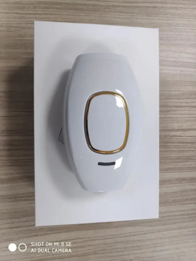 Foldable IPL laser hair removal device with sleek ergonomic white and gold design and gold accents