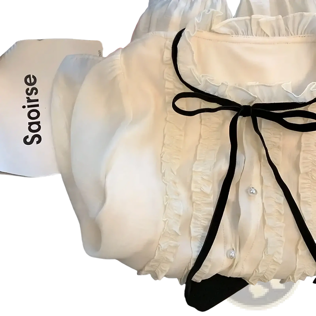 Cream-colored French chic lace bow tie blouse with delicate ruffles black ribbon tie and pearl buttons at neckline