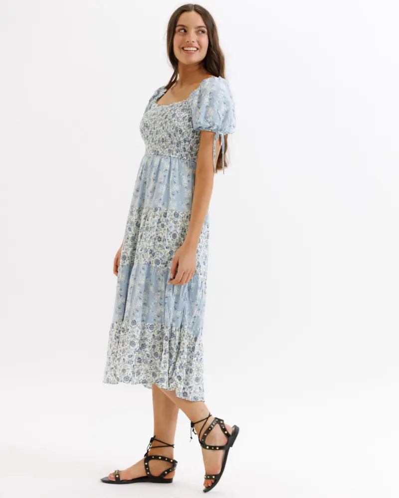 A light blue floral print tiered midi dress with puffed short sleeves and a square neckline for elegant occasions