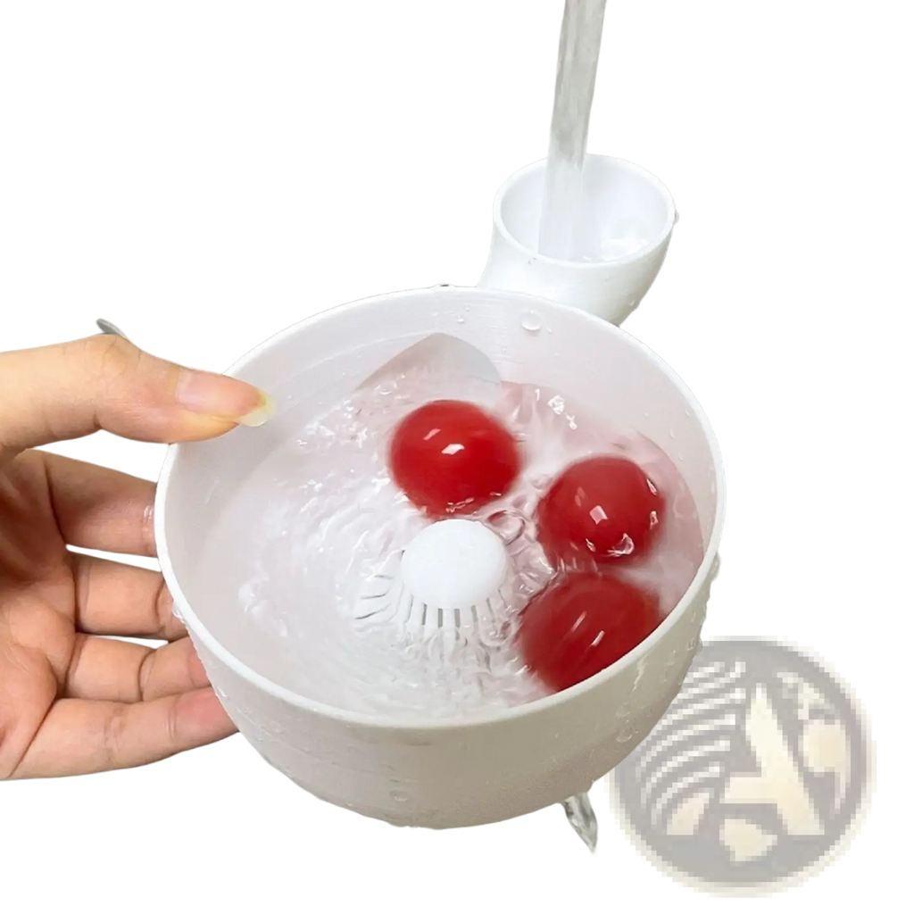 White plastic fruit washing bowl with built-in brush and spout holding three red cherry tomatoes in water