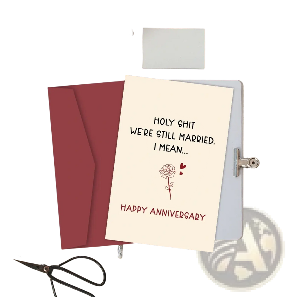 Cream-colored funny anniversary card for husband with black and red text reading holy shit we’re still married