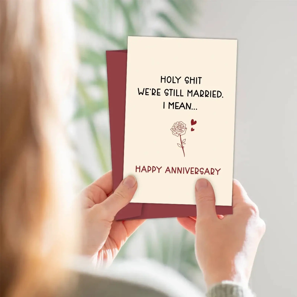 Funny anniversary card for husband cream colored with maroon text and rose drawing held against maroon envelope