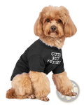 A fluffy tan dog wearing a black short-sleeved funny dog t-shirt with cute but psychic printed in white