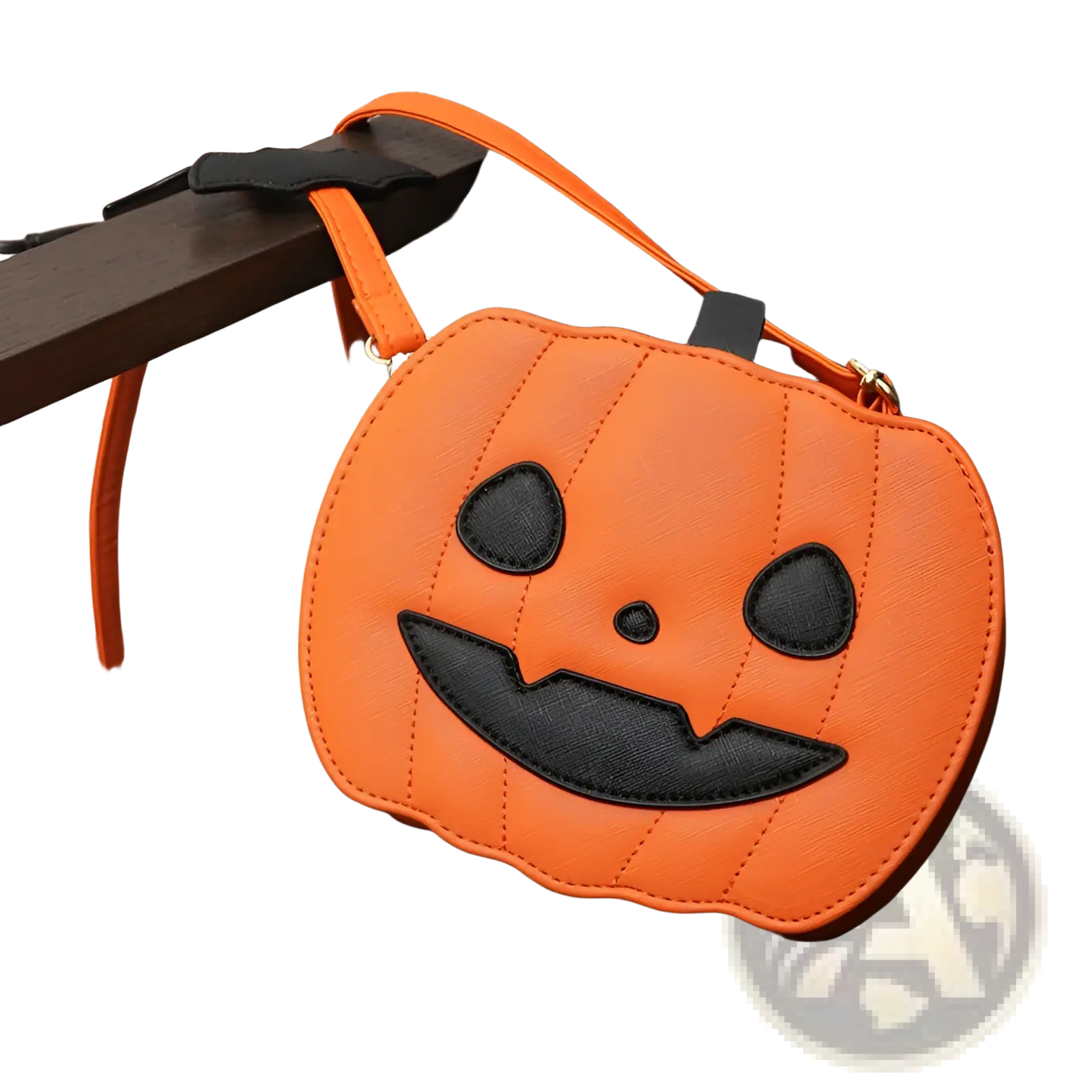 Orange pumpkin-shaped crossbody bag with black embroidered face and detachable bat charm for festive use