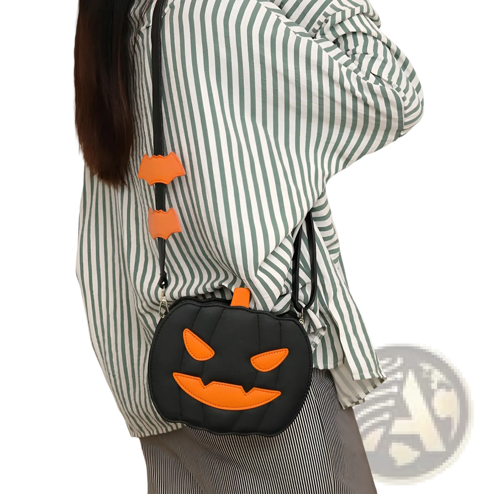 Black quilted pumpkin-shaped crossbody bag with orange stitched face and detachable bat charms on the strap