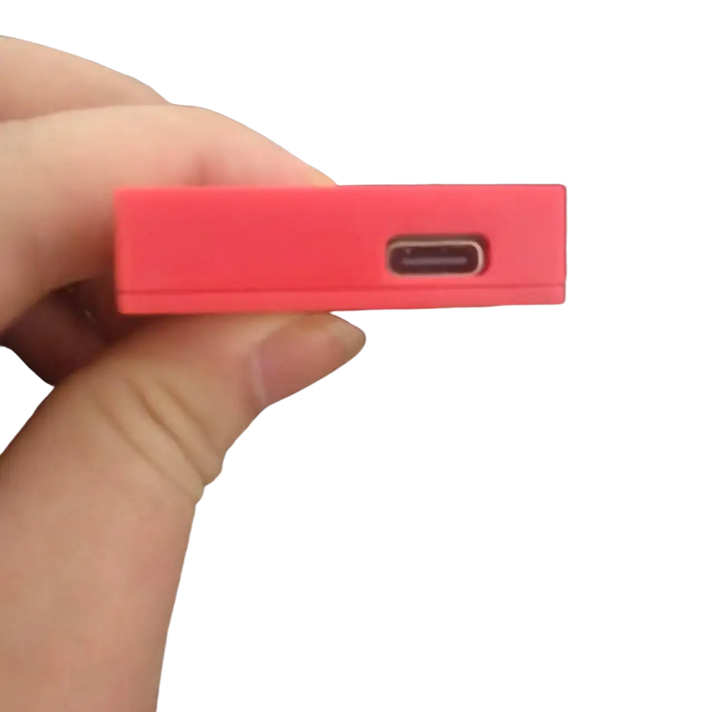 Red rectangular usb-c charging adapter held in hand next to pink game card storage box v2 accessory case