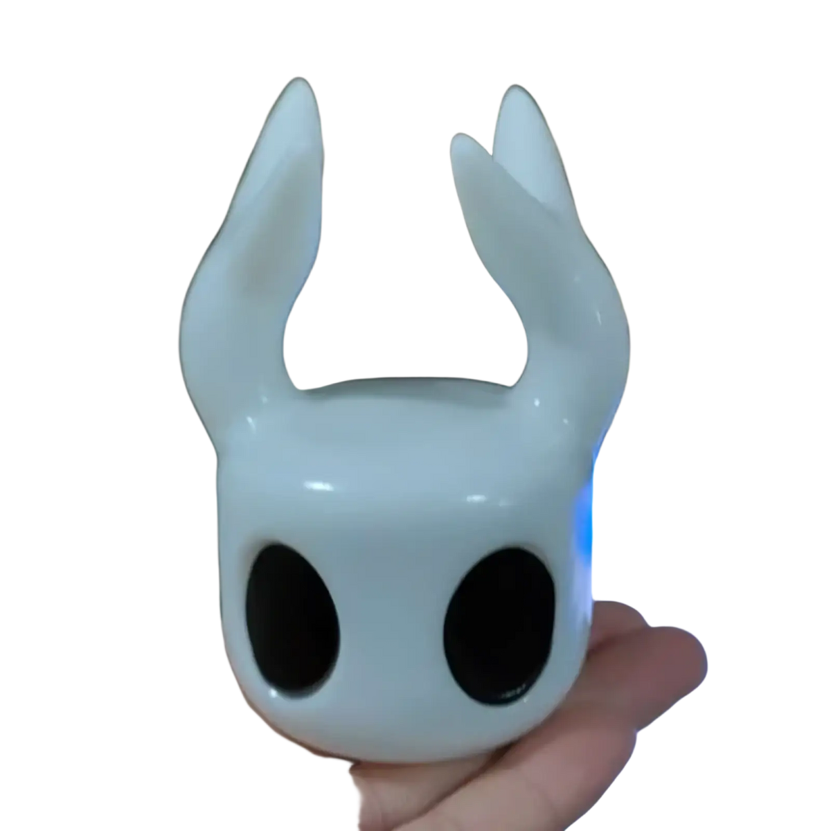 Glossy white ceramic hollow knight figurine with black eyes and horn-like protrusions game controller stand display