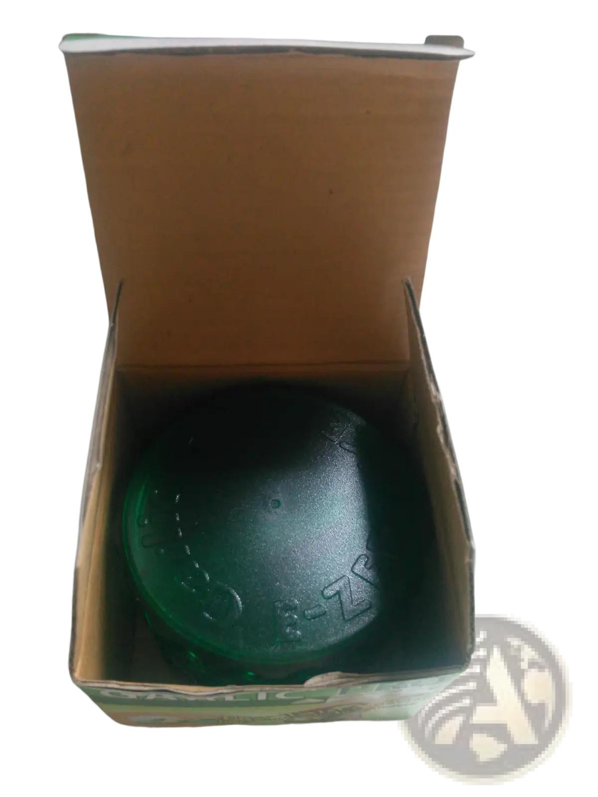 A dark green textured soap bar in a cardboard box next to the garlic pro manual grinder and peeler kitchen tool