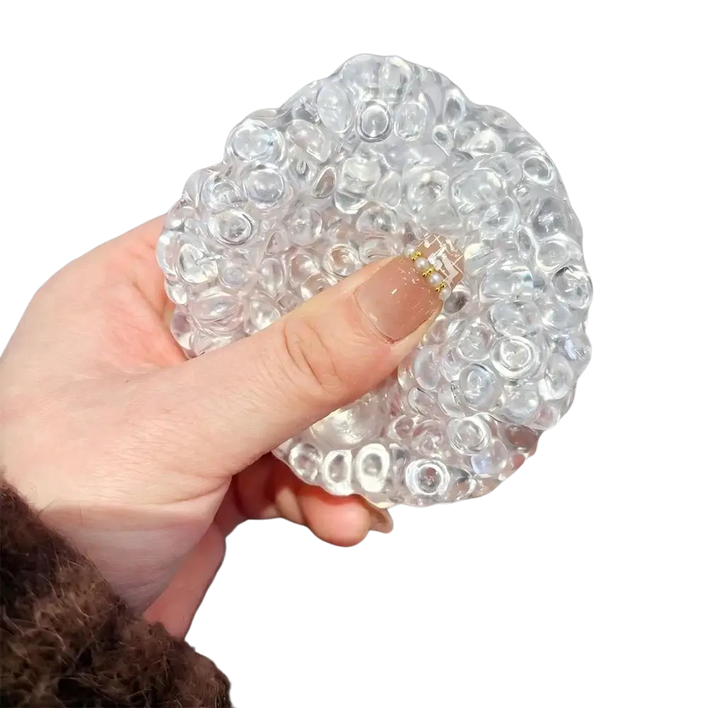 Clear transparent gel ice bead stress relief squeeze toy with textured rounded bubbles and small gold-colored clasp at center