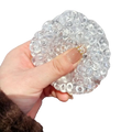 Clear transparent gel ice bead stress relief squeeze toy with textured rounded bubbles and small gold-colored clasp at center