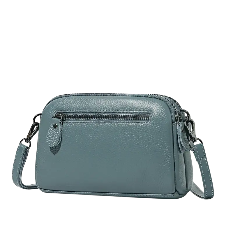 A sleek slate blue genuine leather crossbody bag for women with textured surface and black zipper accents