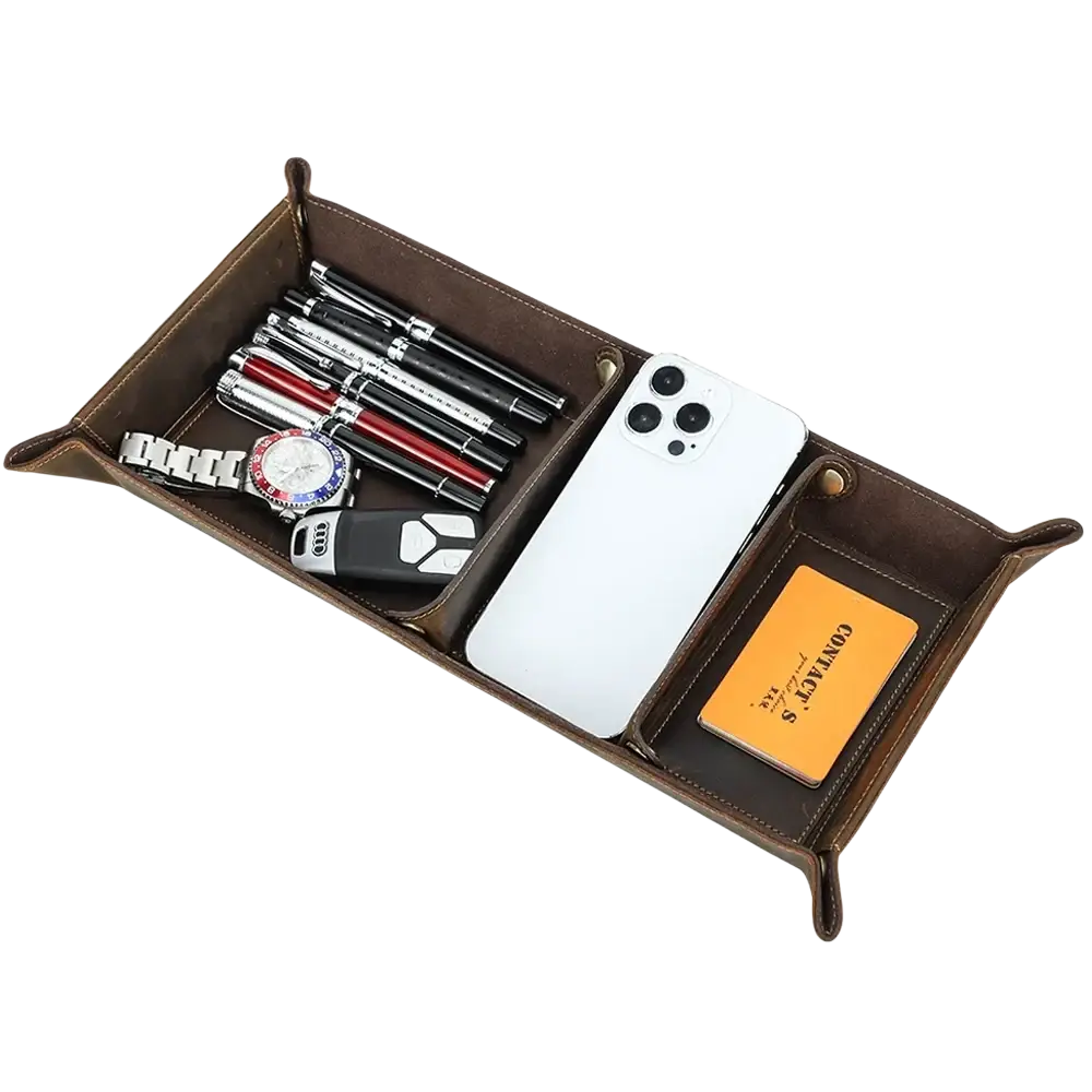 Genuine leather desktop organizer tray in brown with divided compartments holding pens, watch, phone, and cards
