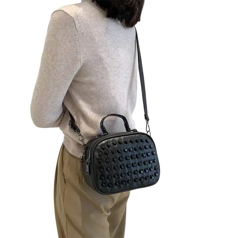 Black genuine leather shoulder bag with quilted texture, studded design, top handle, and phone pocket for convenience