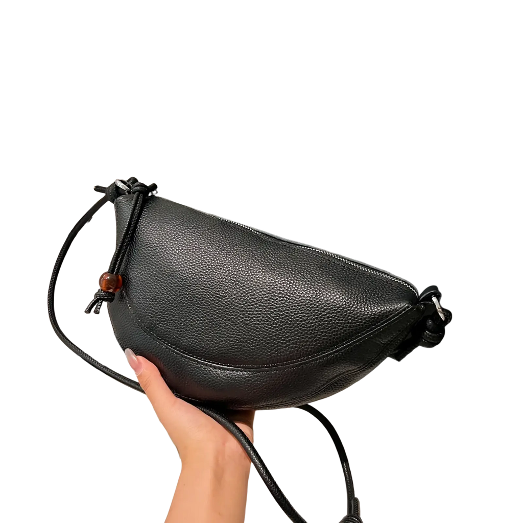 Black genuine leather shoulder bag featuring pebbled texture, adjustable strap, and wooden bead accent crossbody style