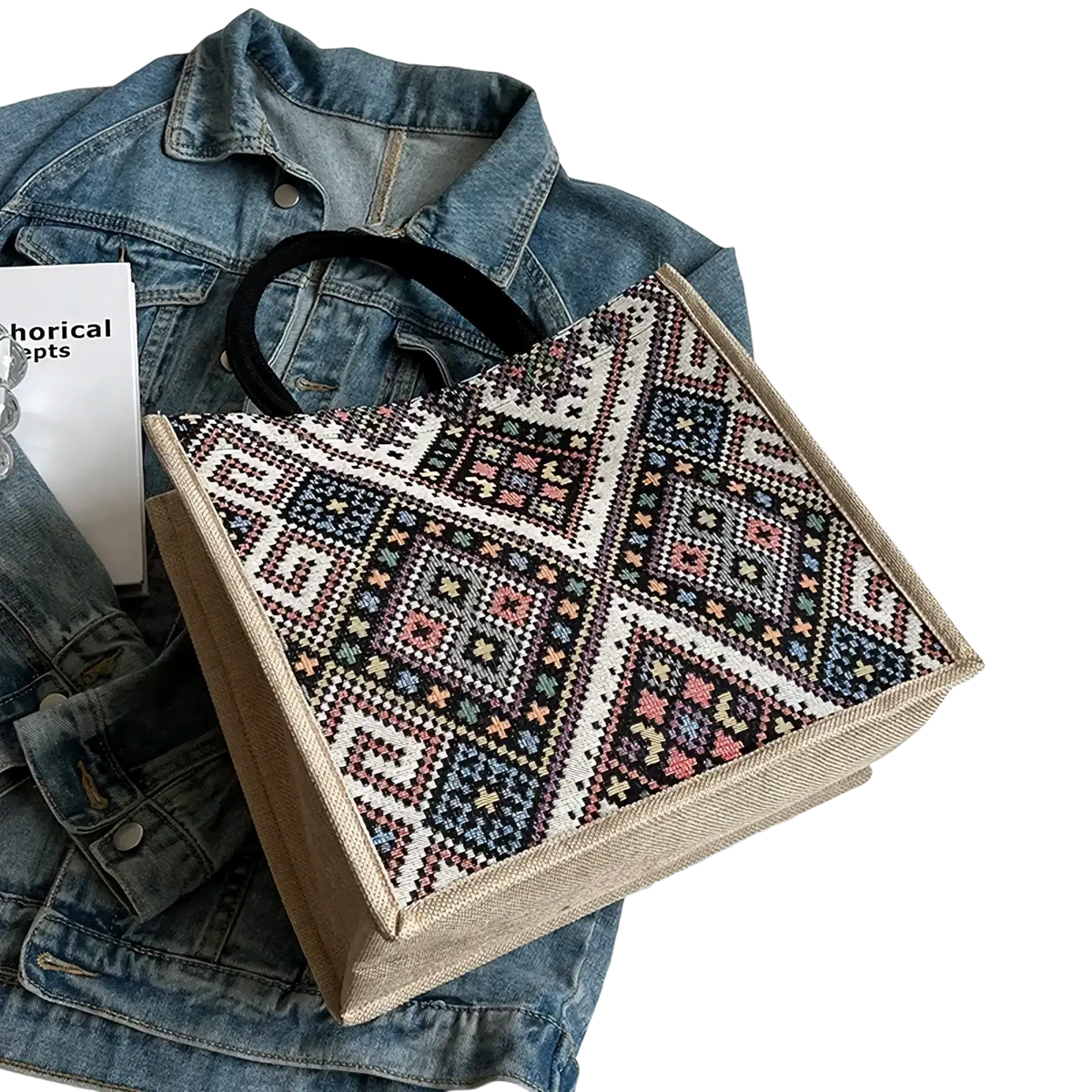 A beige canvas tote bag with vibrant black white pink and blue geometric embroidered pattern for casual commuting