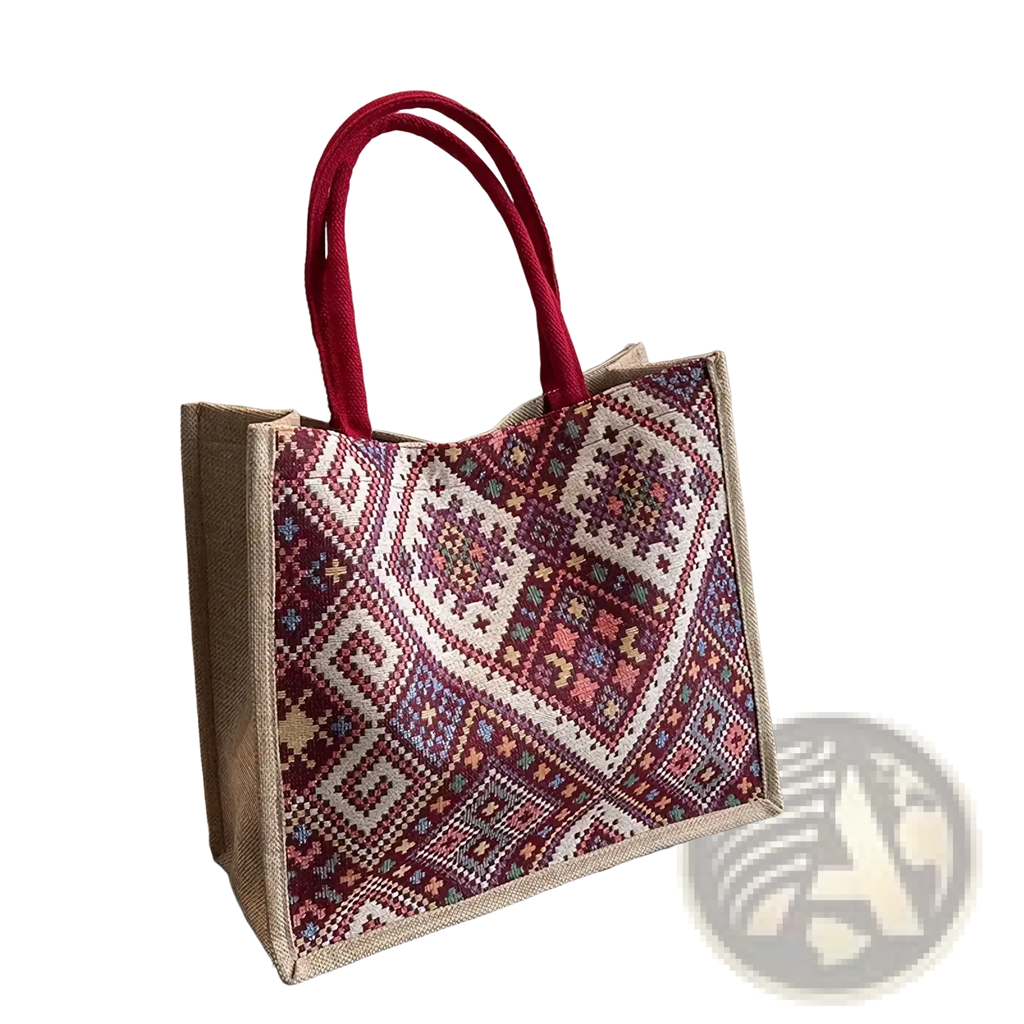 A large woven canvas tote bag with red handles and a vibrant maroon cream pink and blue geometric pattern